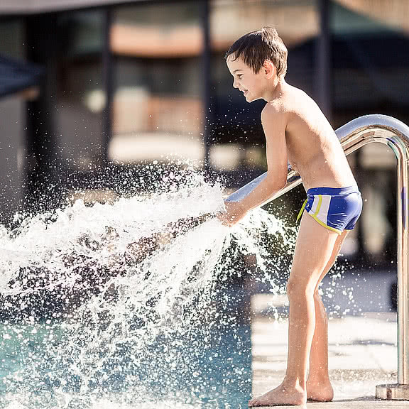 Children playing in the outdoor pool in the wellness and family hotel Sonnen Resort