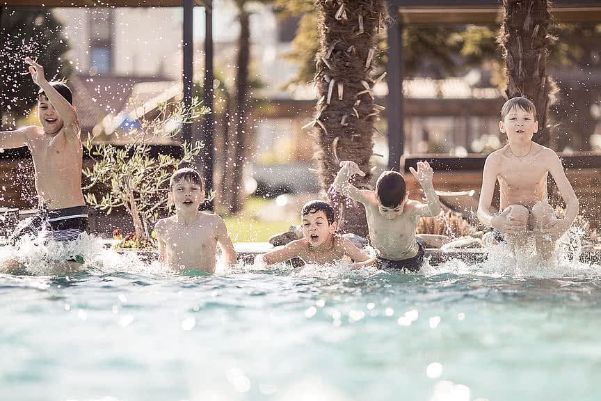 Children playing in the outdoor pool in the wellness and family hotel Sonnen Resort