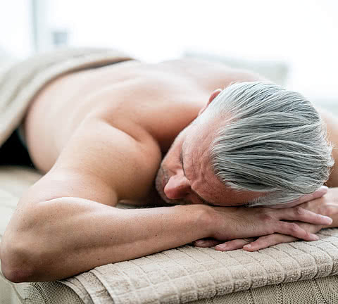 Handsome man lying down relaxing at the spa and ready to get a massage - male beauty concepts