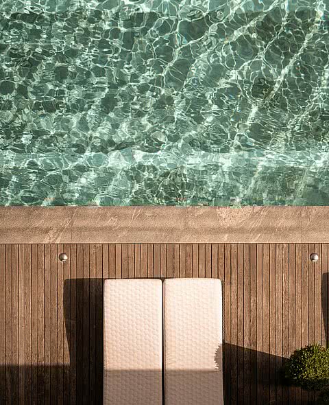 Sonnendeck mit Liegen am glasklaren Pool im Sonnenresort Wellnesshotel in Südtirol.